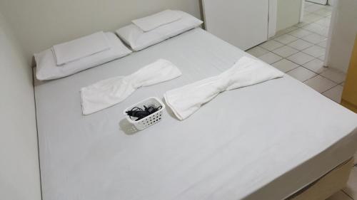 Una cama blanca con sábanas blancas y una cesta. en Ponta Verde, en Maceió