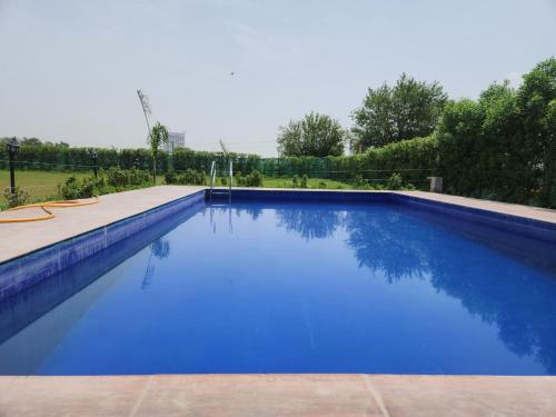 a large swimming pool with blue water at Aradiya Farm House in Noida