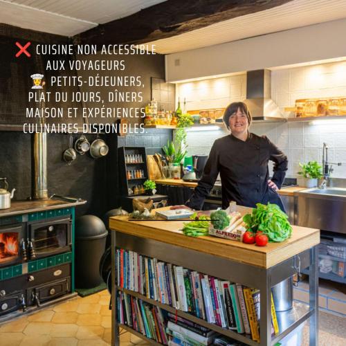 a woman standing behind a counter in a kitchen at Les Portes Neuves! in Belloc-Saint-Clamens