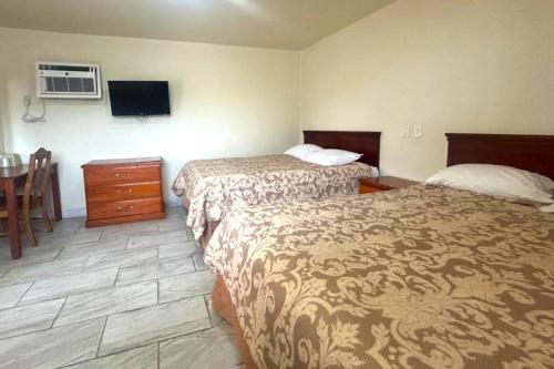 a hotel room with two beds and a table at Pen Ann by Capital O Pharr-McAllen TX in Pharr