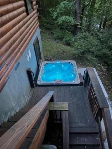 a hot tub on a deck next to a house at Stoney Brook Cabin in Boone