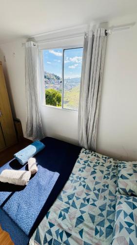 a bedroom with a bed with towels and a window at Cond Millenium residênce in Juiz de Fora