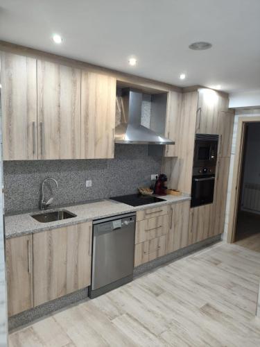 a kitchen with wooden cabinets and a sink and a stove at Luz De Luna in Negreira