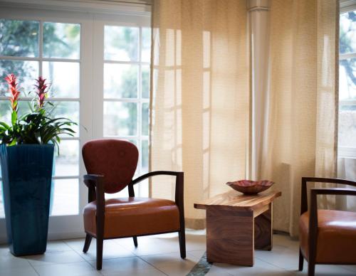 a room with a chair and a table and windows at Coconut Waikiki Hotel in Honolulu