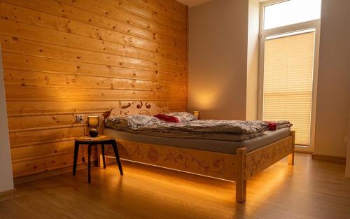 a bedroom with a bed with a wooden wall at Apartament Oravski, blisko Term Chochołowskich, Tatry i Oravice, cisza, widok, parking in Suchá Hora