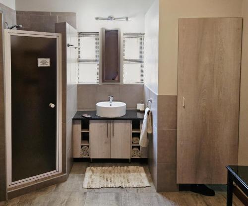 a bathroom with a sink and a mirror at Rest-a-While Guest House - Pretoria in Pretoria