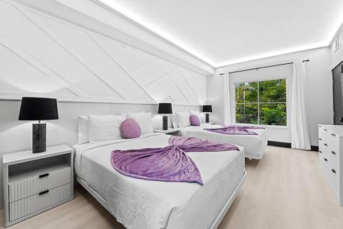 two beds in a white bedroom with purple pillows at Hawthorn Suites Suite Near Universal & I-Drive in Orlando