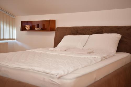 a bed with white sheets and a brown headboard at SIBE Apartments in Banja Luka