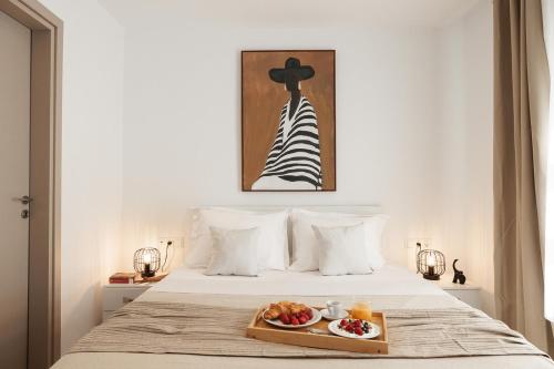 a bed with a tray with a plate of food on it at Blue Cyclades Villas in Kastraki