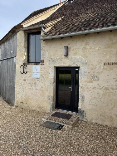 a stone building with a black door and a window at RELAI VALDIEU in Courgeon