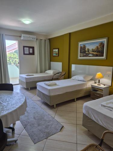 a hotel room with three beds in a room at Pousada Alto Riviera in Macaé