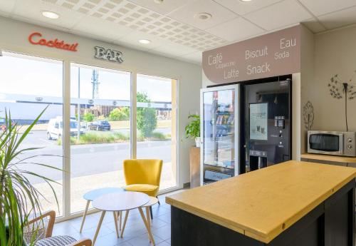 a cafe with a table and chairs and a counter at B&B HOTEL Lieusaint Carré Sénart in Lieusaint