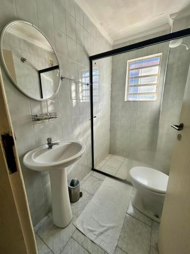 a bathroom with a sink and a toilet and a mirror at Hotel Brasil Pindamonhangaba in Pindamonhangaba