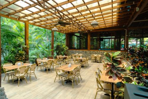 a restaurant with wooden tables and chairs and plants at Bungalows Beachfront Hotel in Punta Uva