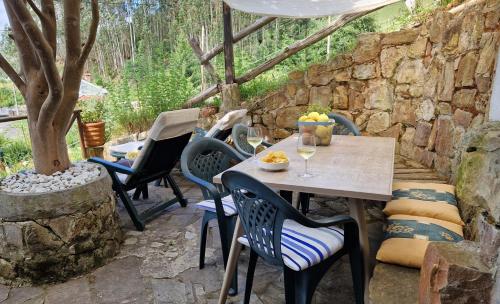 a table and chairs on a patio with a stone wall at La casina de Pili in Villaviciosa