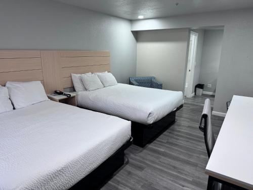a hotel room with two beds and a desk at Travelodge by Wyndham Redding CA in Redding
