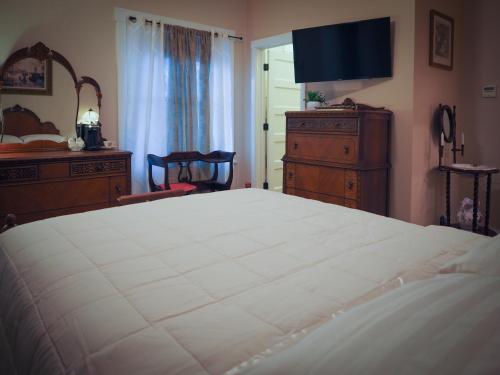 a bedroom with a large white bed and a dresser at El Amador Inn Downtown Tucson in Tucson