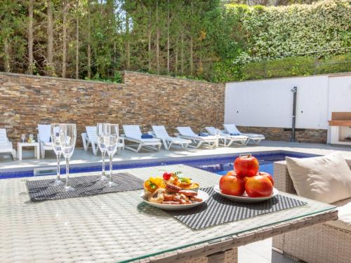 a table with plates of fruit on it next to a pool at Villa Palmbeach by Interhome in Lloret de Mar