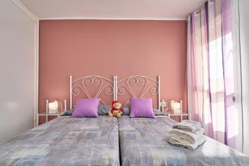 a teddy bear sitting on a bed with purple pillows at Mirador del Mar in Torrox Costa