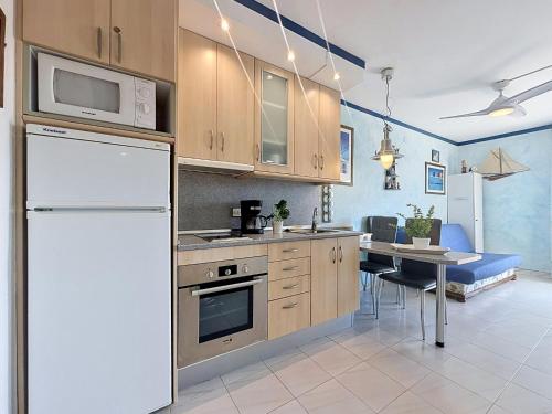 a kitchen with a white refrigerator and a table at Apartment Club Nautic-17 by Interhome in Empuriabrava