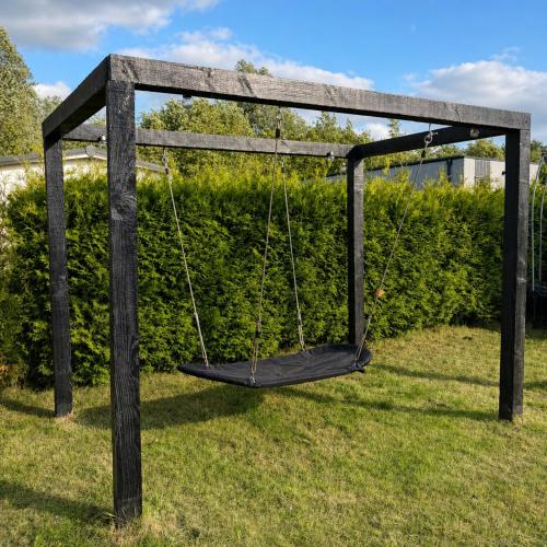 a wooden swing in a yard with grass at Vienna in Dronrijp