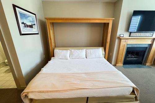 a large bed in a room with a fireplace at Long Trail House 459 in Stratton
