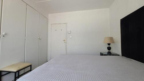 a white bedroom with a bed and a chair at Light Hall in Johannesburg