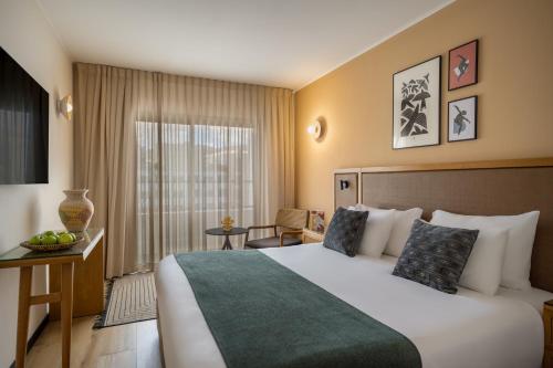 a hotel room with a large bed and a window at Neve Eilat Hotel By Atlas Hotels in Eilat
