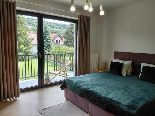 a bedroom with a bed and a balcony with a view at Apartament Parkowa 8 in Myślenice