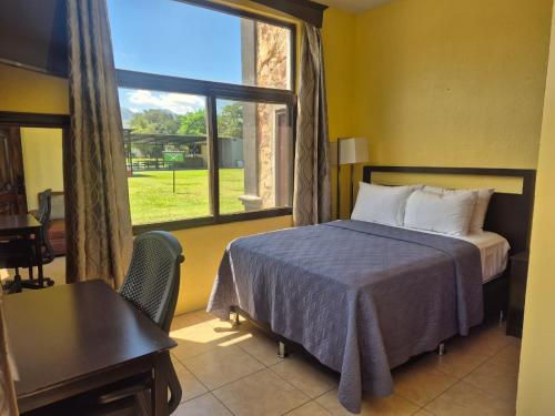 a bedroom with a bed and a large window at Grand Caporal Hotel in Chiquimula