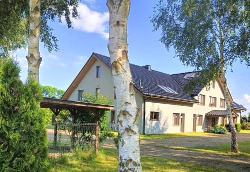 a white house with a black roof at Pensjonat Ślepowron in Międzywodzie