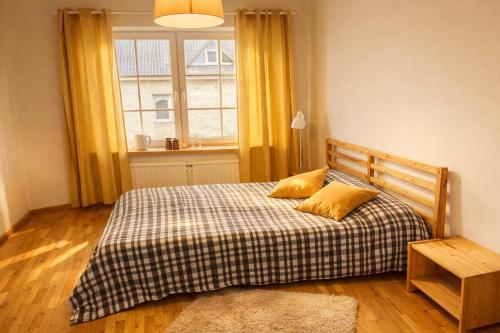 a bedroom with a bed with two pillows and a window at Saulės Namai in Palanga