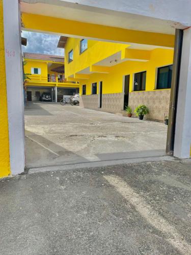 an open door to a yellow building with a parking lot at Pousada ENCANTOS de PERUÍBE in Peruíbe