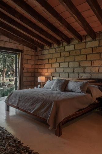 ein Schlafzimmer mit einem Bett in einer Ziegelwand in der Unterkunft Armadillo Mágico in Armadillo