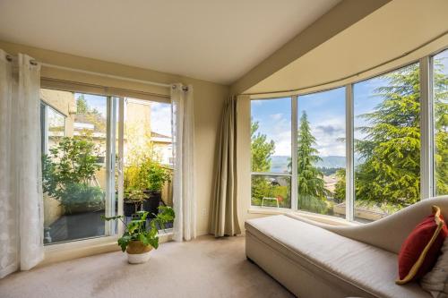 a living room with a couch and large windows at Mountain and Ocean Views Art Deco House in West Vancouver