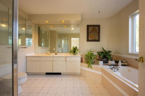 a bathroom with a tub and a toilet and a sink at Mountain and Ocean Views Art Deco House in West Vancouver
