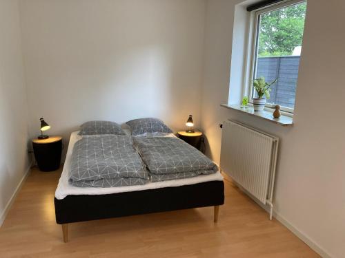 a bedroom with a bed with two lamps and a window at Lille hus i Sydbyen in Silkeborg