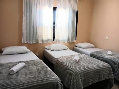 a room with three beds and a window at Pousada Brisa da Mata in Londrina