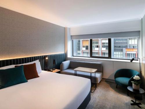 a hotel room with a bed and a chair and a window at Novotel Sydney City Centre in Sydney