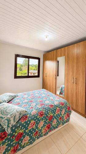 a bedroom with a bed with a floral comforter and a window at Casa Turista in Cambará