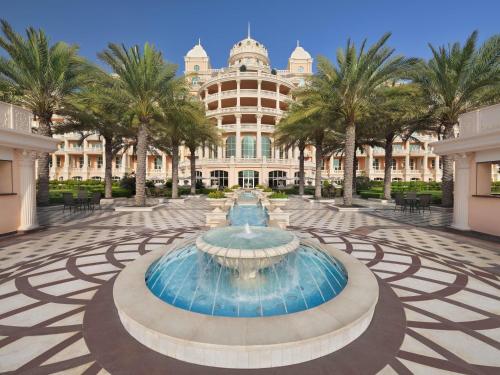 a fountain in front of a building with palm trees at Raffles The Palm in Dubai