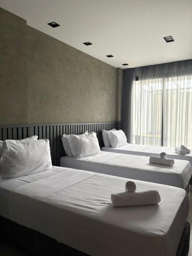 two beds in a hotel room with towels on them at V-Home Flat Hotel in Macaé