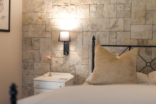 a bedroom with a bed with a stone wall at Clivedon Cottage in Sunland