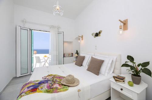 a white bedroom with a large bed with a view of the ocean at Hotel Anixis in Naxos Chora