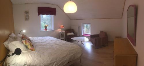 a bedroom with a white bed and a table and chairs at chambre dans les bois in Namur
