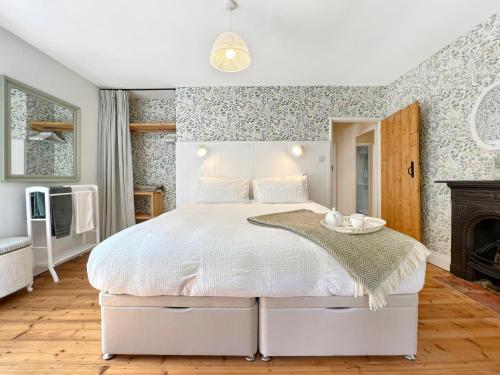 a bedroom with a white bed and a fireplace at Glen Cottage Porlock in Porlock