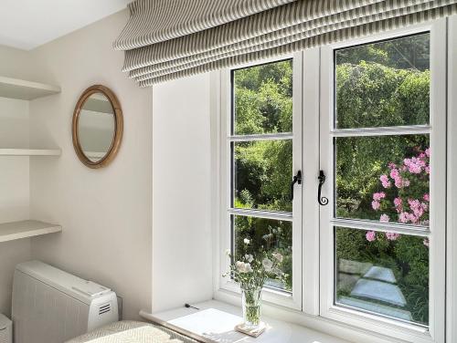 a window with a vase of flowers on a table at Glen Cottage Porlock in Porlock