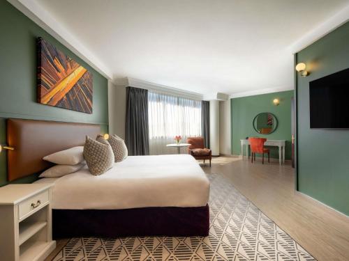 a hotel room with a large bed and a living room at Mövenpick Hotel Windhoek in Windhoek