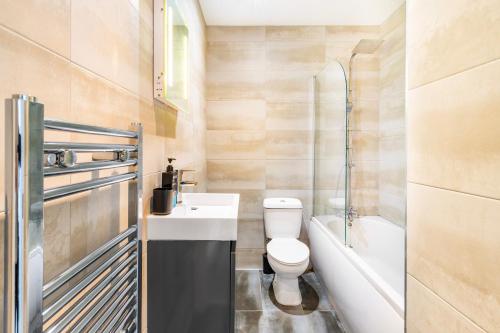 a bathroom with a toilet and a sink and a tub at Stylish Central Location Apartment in Norwich