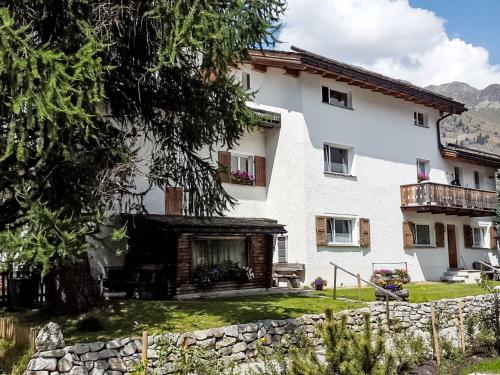 a large white house with a stone wall at Apartment Studio Chesa Marias by Interhome in Sils Maria